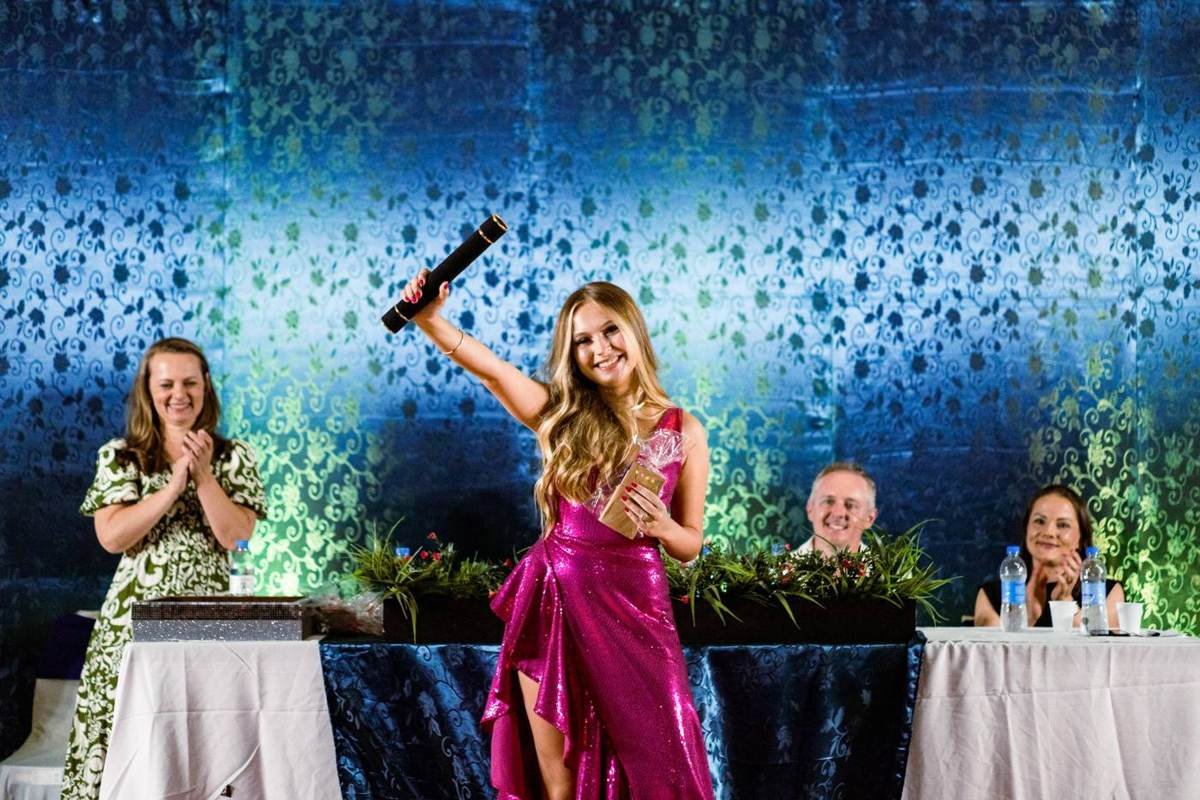 Palco decorado da colação de grau, com formanda erguendo o canudo